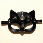 Masque en cuir noir style félin avec rivets métalliques, présenté à plat sur fond beige.