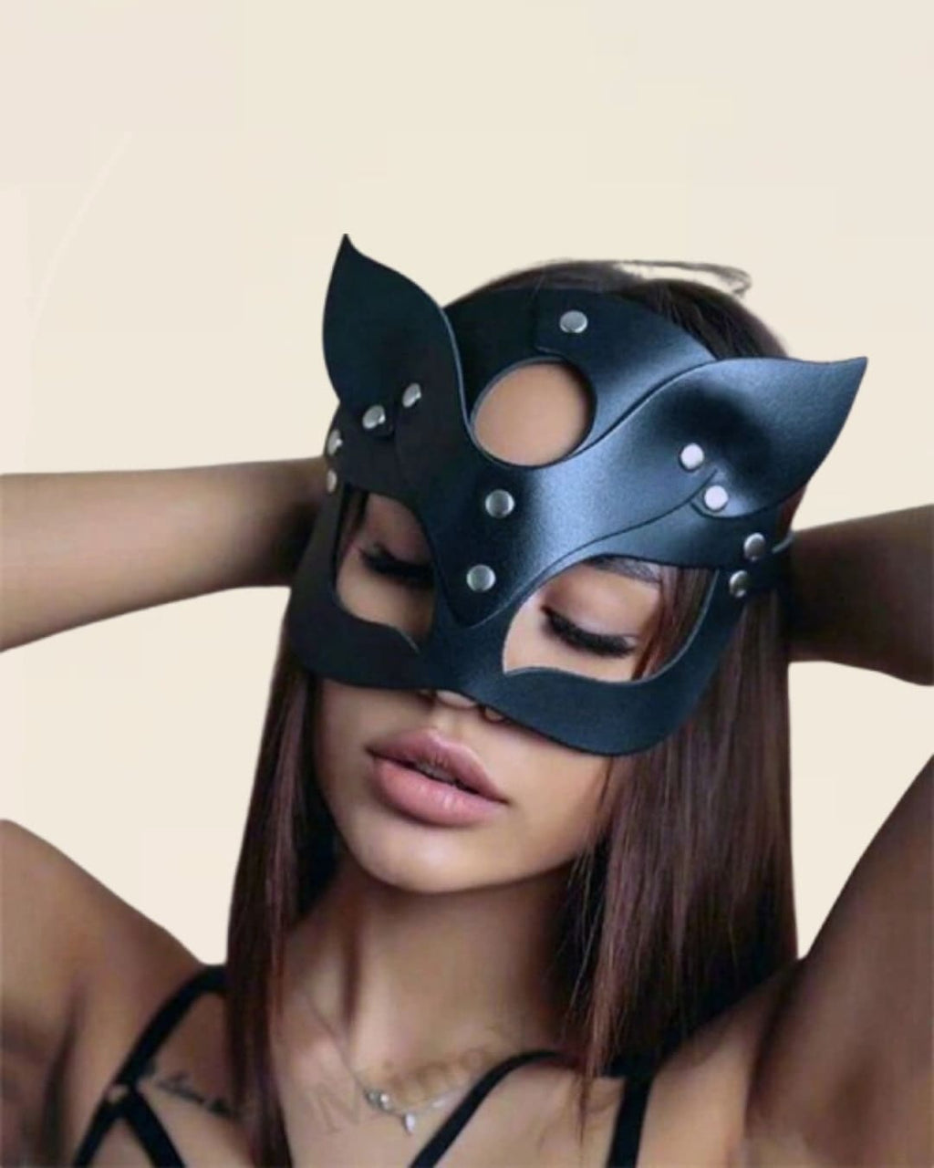Femme portant un masque en cuir noir style chat avec rivets, look sensuel et audacieux.